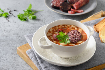 Asturiana traditional fabada with haricot, blood sausage served fresh crispy toast on gray stone table. View from above. Copy space. Spanish cuisine.
