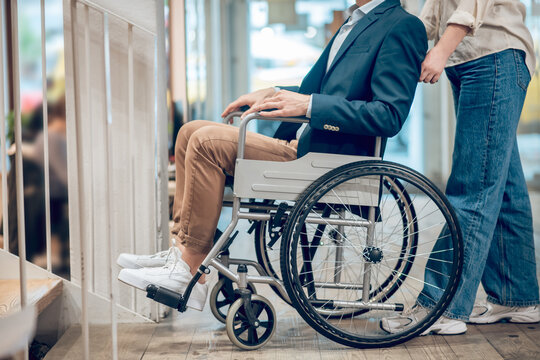 Man in wheelchair and accompanying assistant