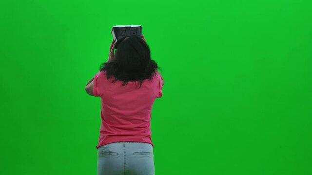 Portrait of young female African American with virtual reality headset or 3d glasses . Black woman with curly hair poses on green screen in the studio. Close up. Slow motion ready 59.97fps.