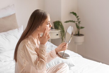 Teenage girl with acne problem looking in mirror at home