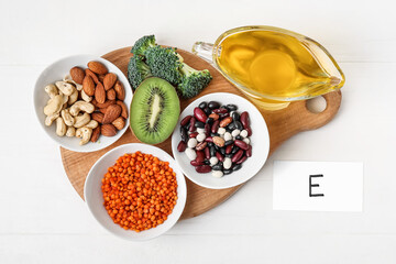 Board with healthy products rich in vitamin E on light wooden background