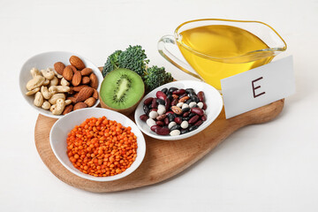 Board with healthy products rich in vitamin E on light wooden background