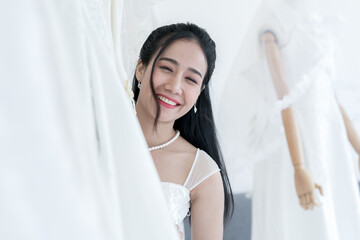 Pretty asian woman choosing and trying on dress in a Wedding dress shop. Happy Bride portrait concept