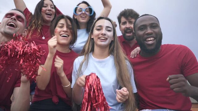 Group of multiracial sport supporters fans in red and blue colours cheering, singing and celebrating the victory of their football national team