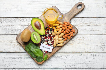 Board with healthy products rich in vitamin E on light wooden background