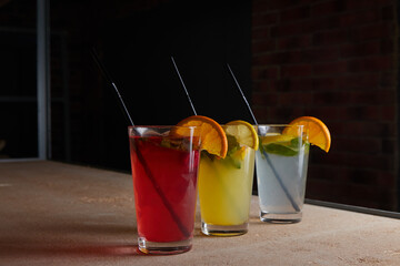 on the table, soft drinks, various cocktails, a glass with a straw and a slice of lemon, a blurred background