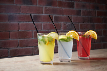 on the table, soft drinks, various cocktails, a glass with a straw and a slice of lemon, a blurred...