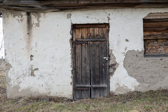 An old wooden door in a ruined farm building with peeling plaster.