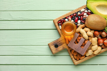 Board with healthy products rich in vitamin E on color wooden background
