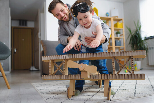 Father playing with toddler son. Playing with cardboard airplane