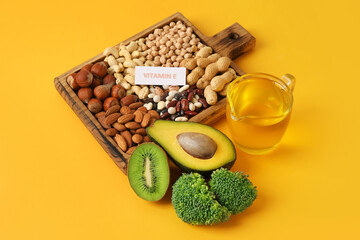 Board with healthy products rich in vitamin E on color background