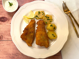 Breaded pike perch fillets with parsley potatoes and sauce tartar.