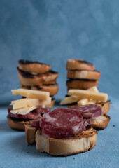 Salami and cheese with toast on a textured background. It is a concept of fast food made at home. Homemade cold cuts with delicious country toasts.