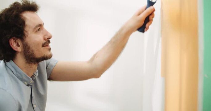 DIY Man paints a wall orange with a small roller