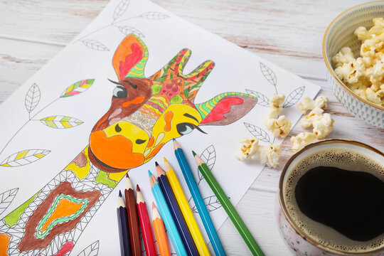 Coloring picture, pencils and cup of coffee on wooden background, closeup