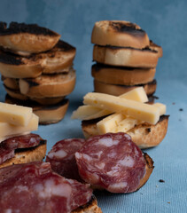 Salami and cheese with toast on a textured background. It is a concept of fast food made at home. Homemade cold cuts with delicious country toasts.
