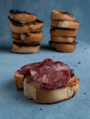 Salami and cheese with toast on a textured background. It is a concept of fast food made at home. Homemade cold cuts with delicious country toasts.
