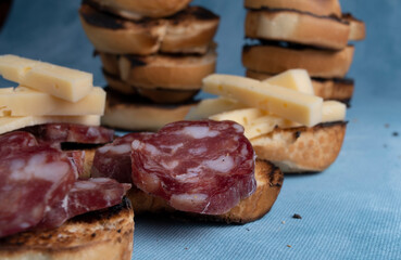 Salami and cheese with toast on a textured background. It is a concept of fast food made at home. Homemade cold cuts with delicious country toasts.
