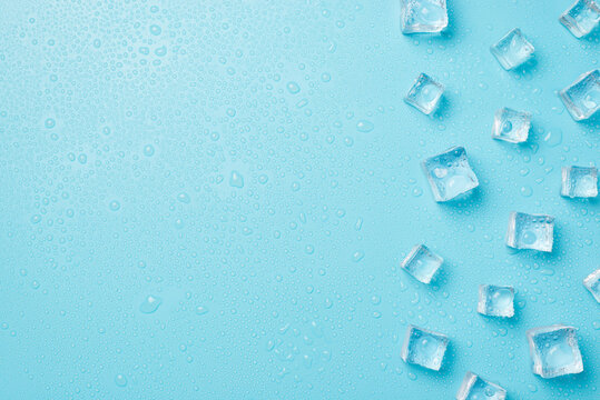 Overhead photo of pile of cubes ice and drops isolated on the blue background with empty space