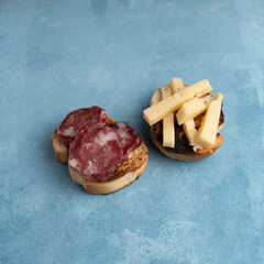 Salami and cheese with toast on a textured background. It is a concept of fast food made at home. Homemade cold cuts with delicious country toasts.
