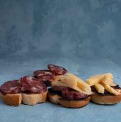 Salami and cheese with toast on a textured background. It is a concept of fast food made at home. Homemade cold cuts with delicious country toasts.
