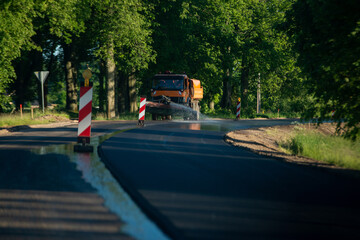 heavy truck pours water on the road during road repairs. Dust removal, environmental protection. Dust irrigation of the road