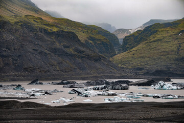 The Solheimajokull Glacier in Iceland showing icebergs and calved ice in the lagoon as ice calves...