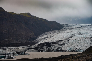 The Solheimajokull Glacier in Iceland showing icebergs and calved ice in the lagoon as ice calves...