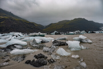 The Solheimajokull Glacier in Iceland showing icebergs and calved ice in the lagoon as ice calves...