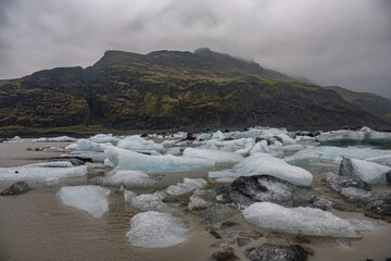 The Solheimajokull Glacier in Iceland showing icebergs and calved ice in the lagoon as ice calves...