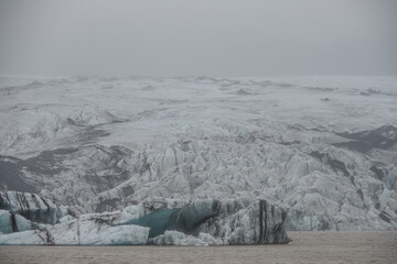 The Solheimajokull Glacier in Iceland showing icebergs and calved ice in the lagoon as ice calves...