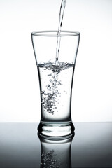 Water pour into the glass on white background