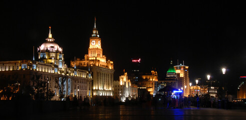 The Bund in Shanghai, China: View of illuminated colonial buildings at night along the Bund in Shanghai. The Bund is popular for tourists and local Shanghai people to walk at night. - obrazy, fototapety, plakaty