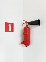 Naklejka premium Red fire extinguisher and fire extinguisher sign isolated on light wall indoors, fire protection template or source