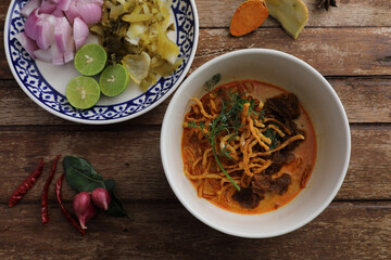 Local northern Thai food Egg noodle curry with beef on wood background