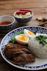 Local Thai food stewed pork leg on rice isolated in wood background
