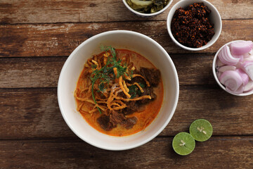Local northern Thai food Egg noodle curry with beef on wood background