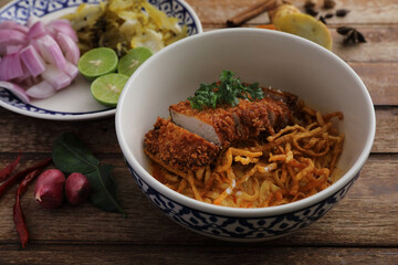 Local northern Thai food Egg noodle curry with fried pork on wood background