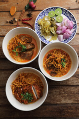 Local northern Thai food Egg noodle curry with pork and beef on wood background
