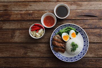 Local Thai food stewed pork leg on rice isolated in wood background