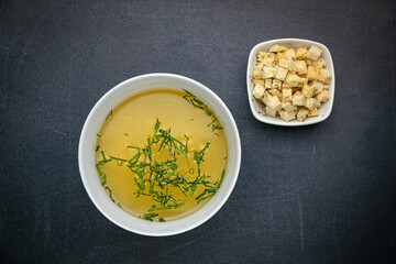 Broth with croutons on a dark table
