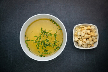 Broth with croutons on a dark table
