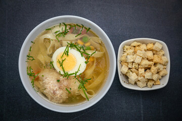 Broth with croutons on a dark table
