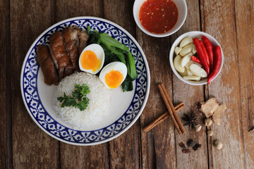 Local Thai food stewed pork leg on rice isolated in wood background