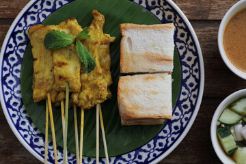 Local Thai food pork satay with oeanut dipping sauce isolated in wood background