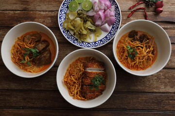 Local northern Thai food Egg noodle curry with pork and beef on wood background