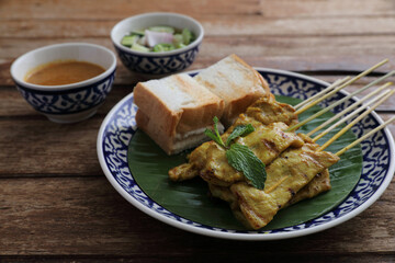Local Thai food pork satay with oeanut dipping sauce isolated in wood background