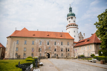 Baroque romantic castle Nove mesto nad Metuji, renaissance chateau with round white clock tower, red tile roof, arched portal entrance, summer sunny day Eastern Bohemia, Czech Republic