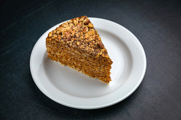Honey cake on a white plate and a dark table
