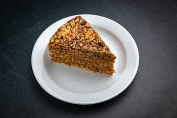 Honey cake on a white plate and a dark table
